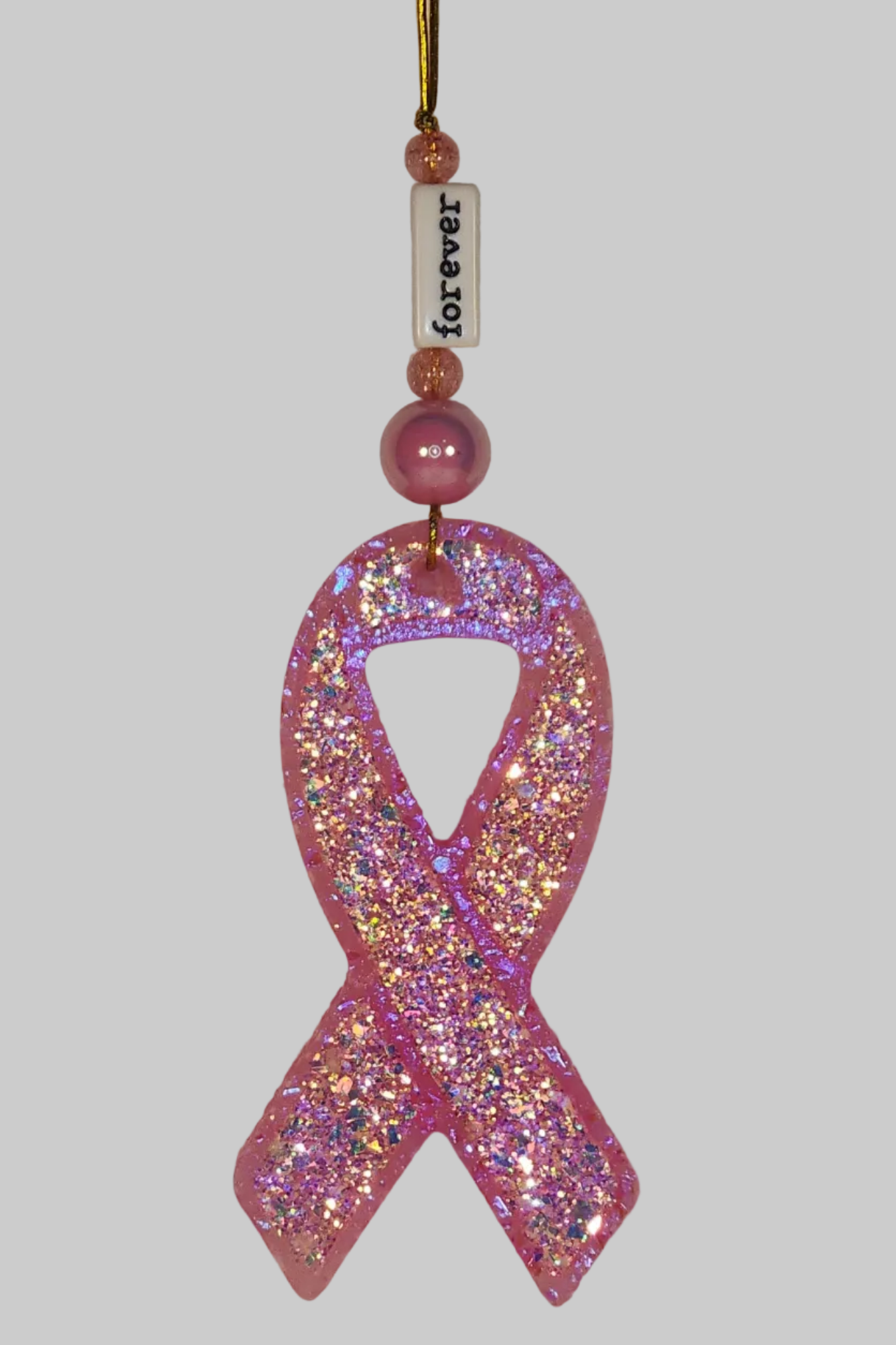 A pink awareness ribbon shaped car air freshener with glitter and a white bead that reads 'Forever'.